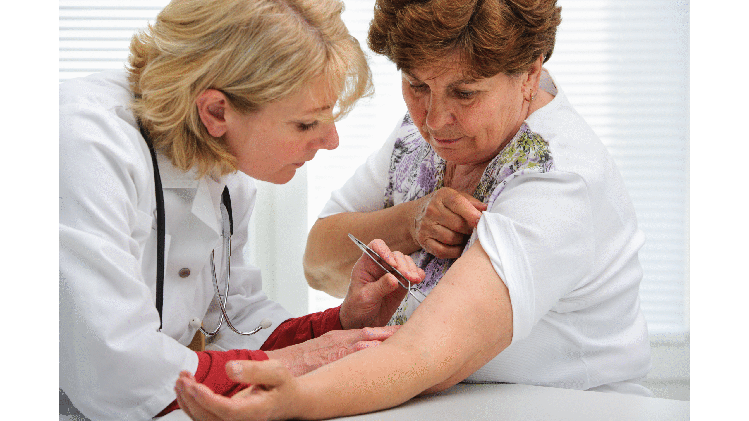 Lekarka bada skórę starszej kobiety za pomocą dermatoskopu.
