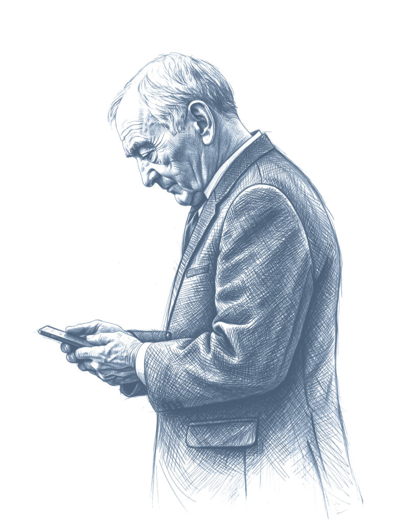 Starszy mężczyzna w garniturze patrzący z zamyśleniem w telefon, trzymając go oburącz.