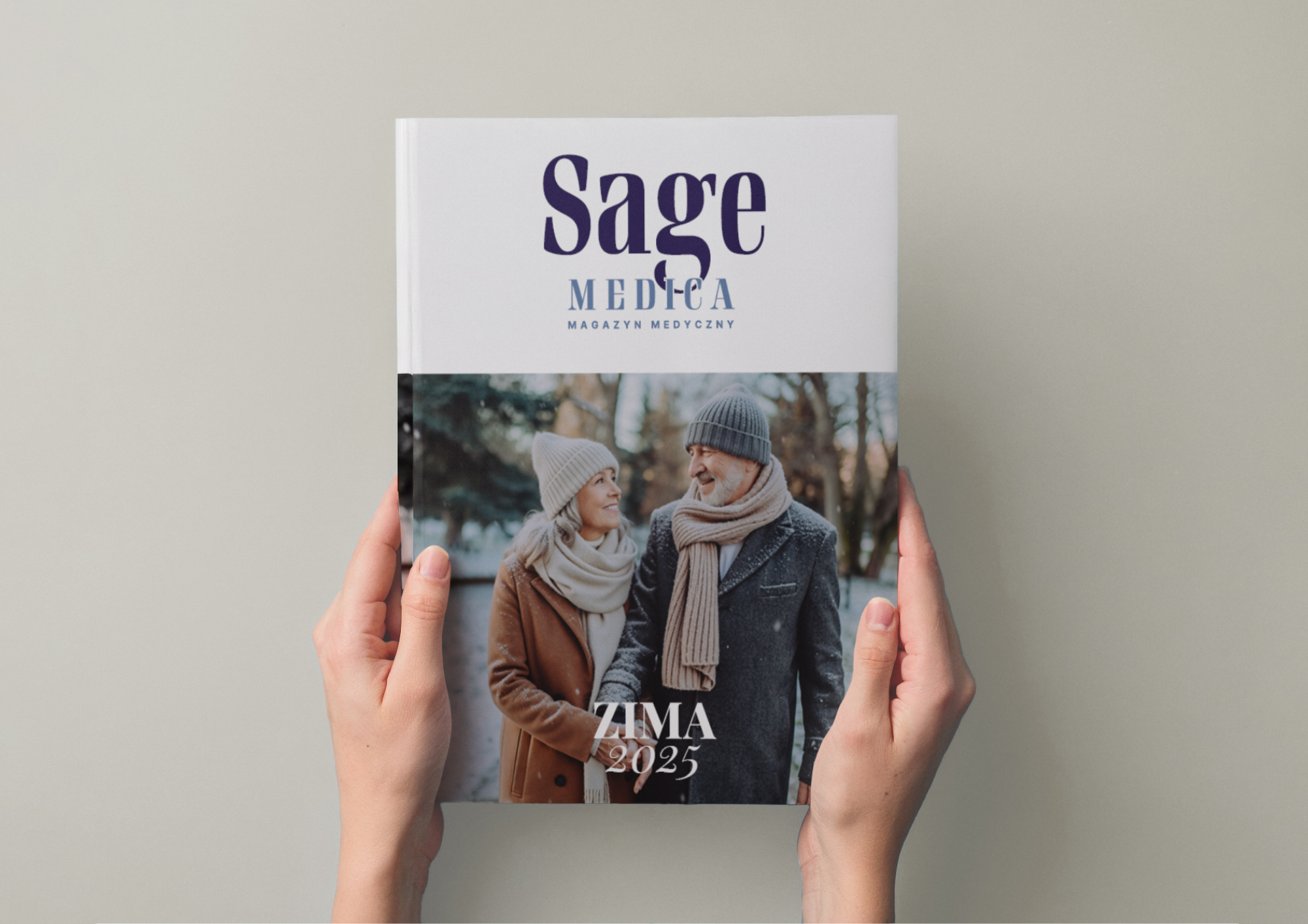 Osoba trzyma w dłoniach zimowy numer magazynu „Sage Medica” z okładką przedstawiającą uśmiechniętą parę spacerującą w śnieżnym parku.
